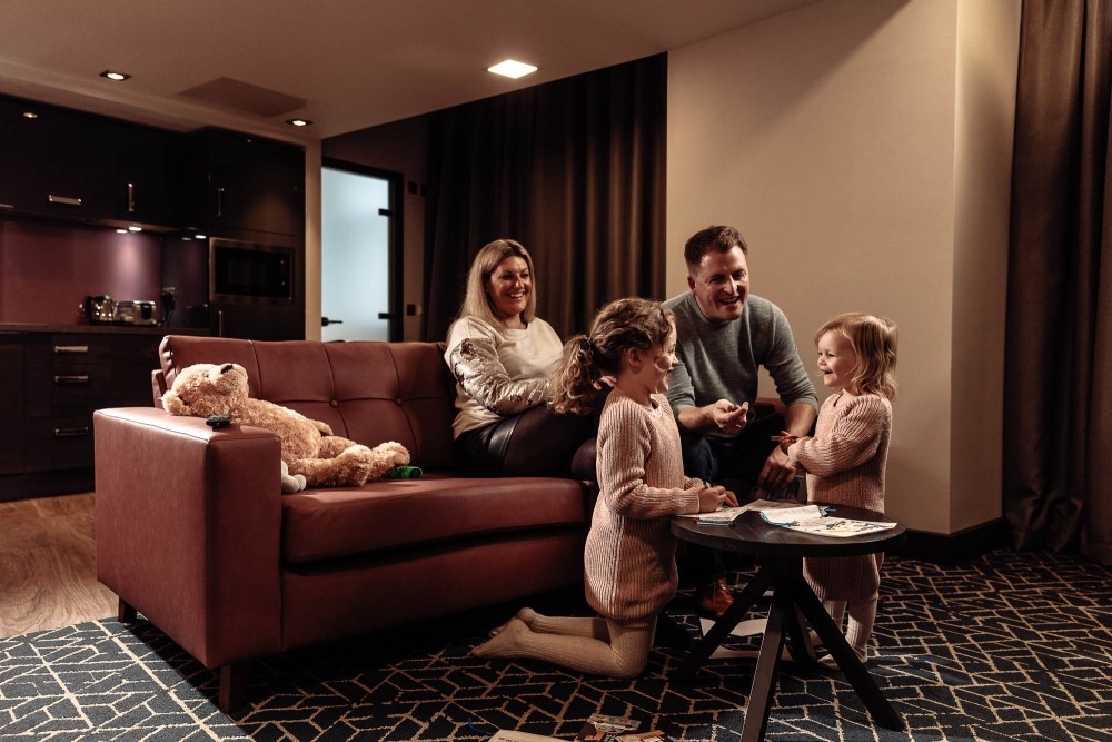 A family sat in the living area of a Roomzzz serviced apartment.