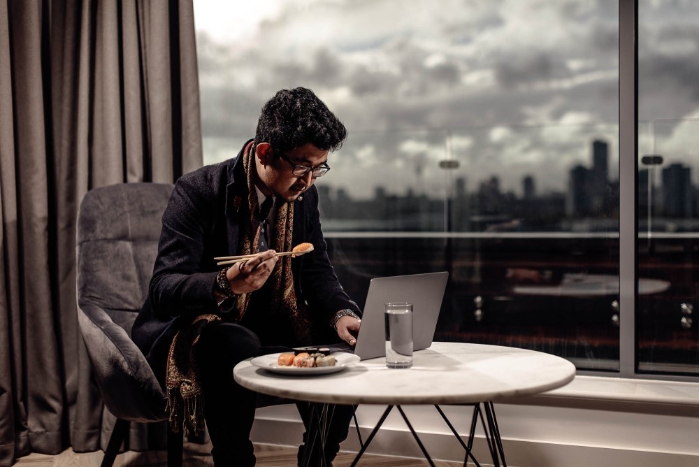 A business traveller working and eating dinner in his Roomzzz apartment.