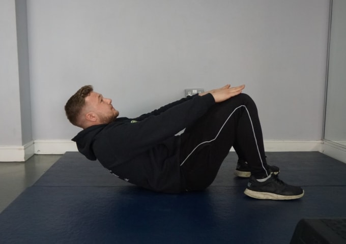 A personal trainer performing a simple bridge exercise for circuit training beginners